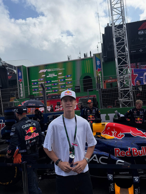 Young man with a paddock pass in front of a Red Bull Racing car