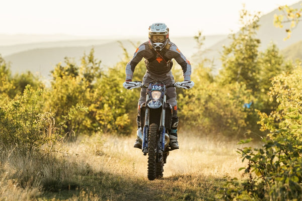 Enduro rider on a dirt bike in dry grassland