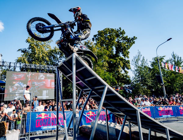 Enduro rider climbing a steel ramp in front of a crowd