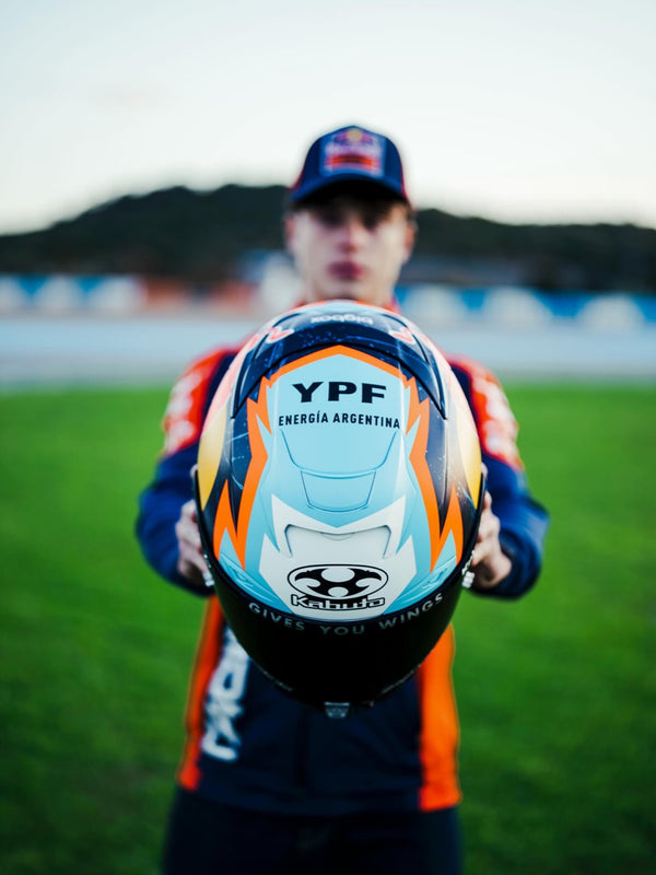 Rider holding his helmet on the grass at a circuit
