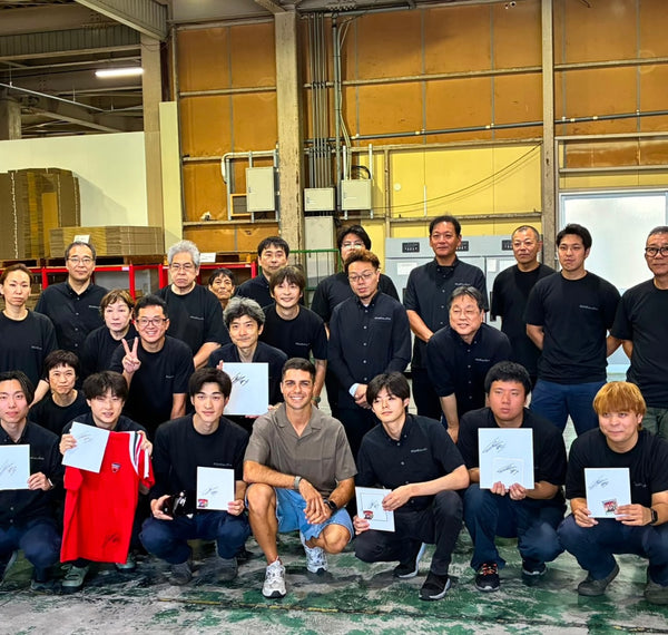 Group photo in a factory, with people holding certificates